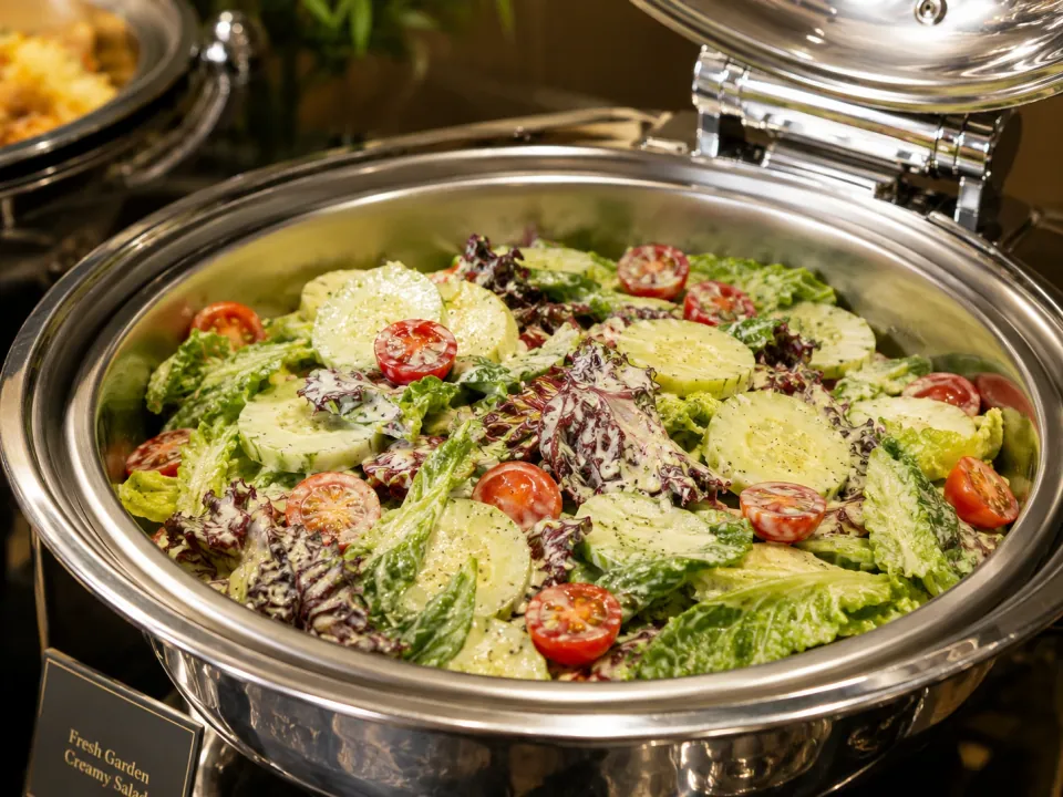 Fresh garden salad with lettuce, cucumber, and tomatoes in a chafing dish